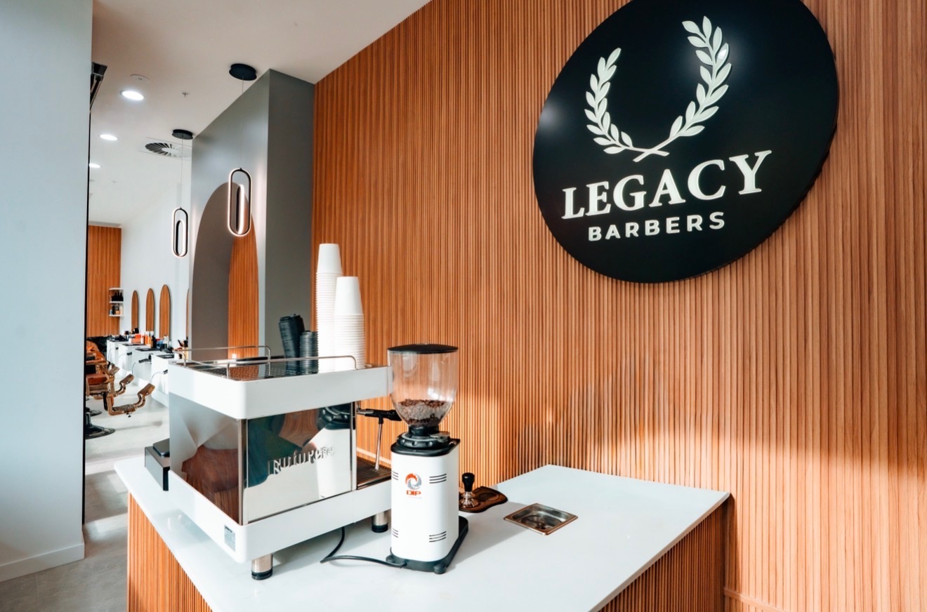 Legacy Barbers reception area with timber wall and shop logo
